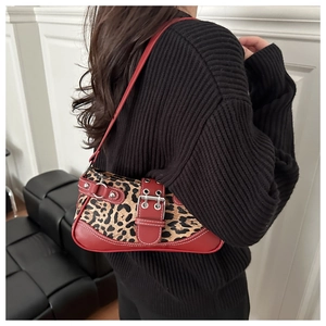 Close-up of leopard print texture and red straps with silver eyelets on an underarm bag