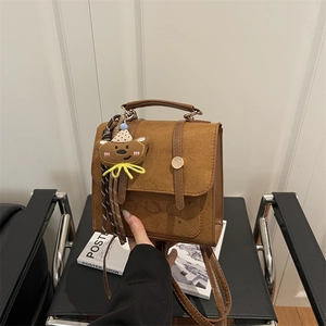 Retro brown suede satchel with bear pendant and gold buckle detail on a neutral background