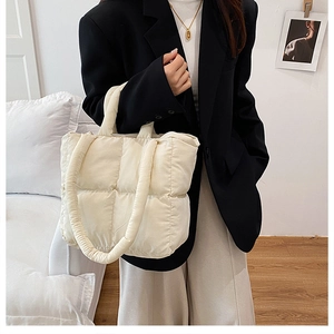 Detailed close-up of cream quilted puffer tote bag on a model in a cozy interior