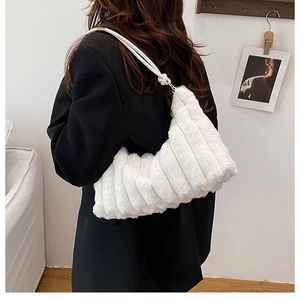 Detail of white plush shoulder bag with vertical stripe texture worn on a black blazer