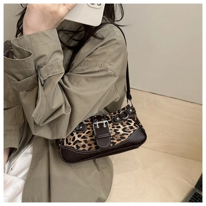 Detailed view of leopard print shoulder bag with vintage buckle and brown trim on a model