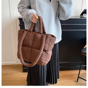 Detail of dark brown quilted puffer tote bag with soft padded handles in a lifestyle setting