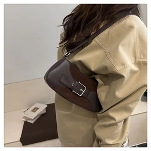 Detail view of dark brown underarm bag featuring suede stitching and metal buckle strap