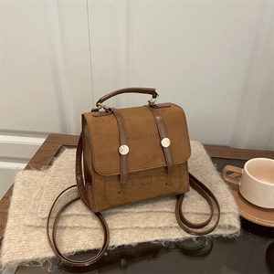 Vintage brown suede backpack with cartoon prints and gold buckle on a cozy knit blanket