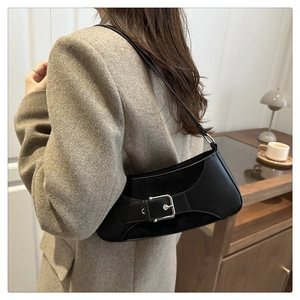Detail of the chic black underarm bag with a silver square buckle worn by a model