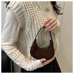 Detail of dark brown suede half-moon handbag featuring gold hardware and elegant texture