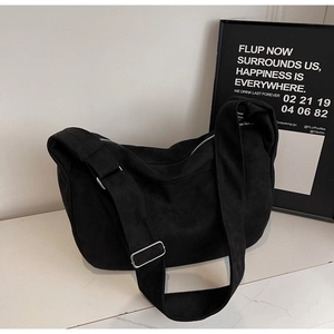 Detail of minimalist black canvas crossbody bag featuring adjustable silver metal buckle strap