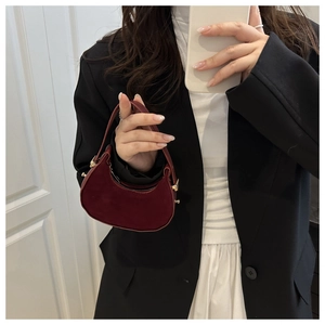 Dettaglio borsa a mezzaluna rosso scuro in similpelle scamosciata con blazer nero