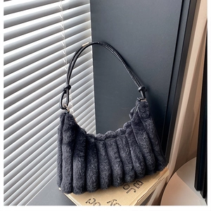 Detailed texture of black plush shoulder bag with vertical pleats and soft faux fur material