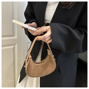 Dettaglio mini borsa a mezzaluna in camoscio marrone con zip e borchie metalliche