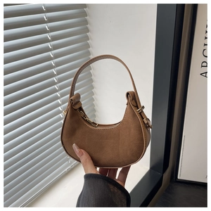 Close-up of brown suede crescent handbag with golden hardware and smooth leather handle