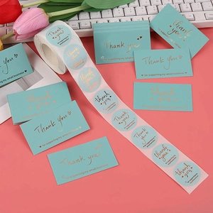 Detail of gold foil Thank You cards and stickers on a stylish desk with tulip flowers