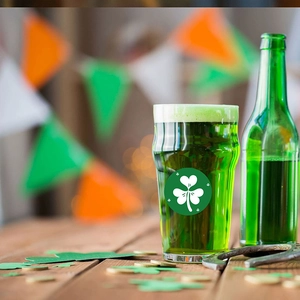 Bicchiere di San Patrizio con birra verde, trifoglio e ferro di cavallo su legno rustico