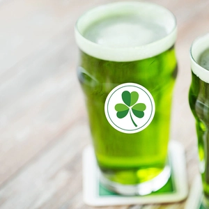Adesivi trifoglio di San Patrizio su vetro con bevanda verde festiva e sottobicchiere bianco