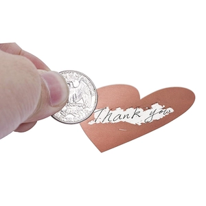 Macro shot of rose gold heart scratch sticker being revealed with a 25 cent coin