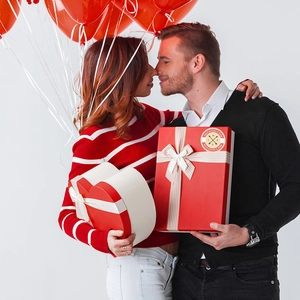 Valentine's Day gift box set with heart shapes and decorative labels held by a couple