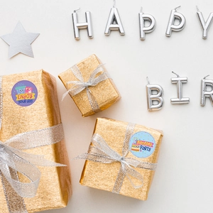 Elegant Happy Birthday labels on gold gift wrap with candles and star decorations
