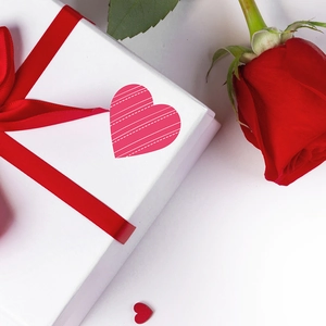 Valentine's Day heart stickers on white gift box with red ribbon and rose