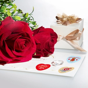 Detail of S925 silver moissanite engagement ring on wedding invitation with red roses