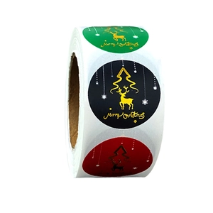 Macro view of Christmas stickers roll featuring gold foil elk and tree on dark backgrounds