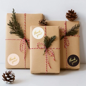 Gold foil Thank You stickers on gift boxes with pine cones and festive cotton twine decoration