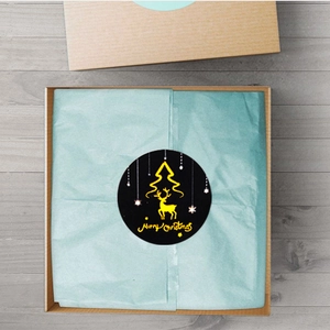 Detail of laser gold Merry Christmas stickers on gift box with elk and tree patterns