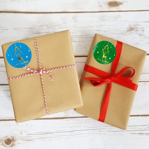 Detail of blue and green Merry Christmas stickers with gold foil reindeer on kraft gift boxes