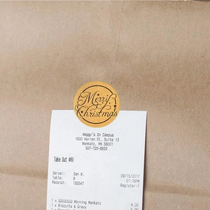 Detail of round gold foil Merry Christmas sticker with star patterns on kraft paper