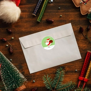 Dettaglio adesivo Babbo Natale su busta bianca con decorazioni natalizie festose