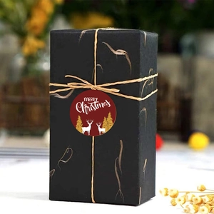 Primo piano di un adesivo rosso Merry Christmas con renna dorata su scatola regalo