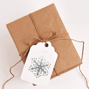 Brown kraft gift box tied with twine and white snowflake tag on white background