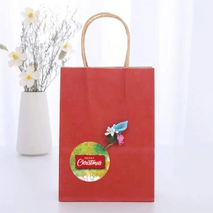 Dettaglio di un sacchetto regalo rosso di Natale con adesivo Merry Christmas e fiori