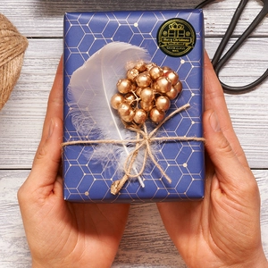 Gift box with black and gold Merry Christmas stickers and navy blue geometric wrapping paper