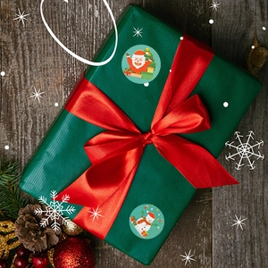 Detail of Santa and Snowman stickers on a green gift box with a red ribbon on wood