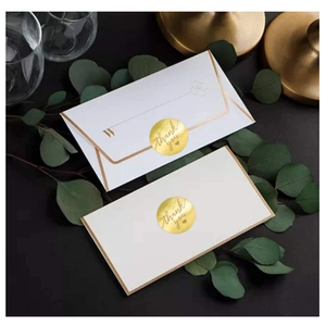 Roll of round gold foil Thank You stickers on white envelopes with eucalyptus leaf decor