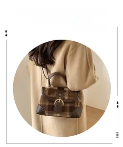 Detail of a brown plaid handbag with leather patchwork and golden horseshoe buckle