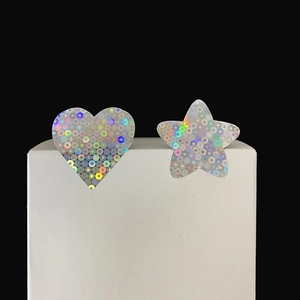 Macro detail of holographic heart and star stickers on white pedestal with laser finish