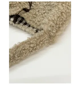 Close-up of reinforced shoulder strap and checkered lining on beige fuzzy tote bag