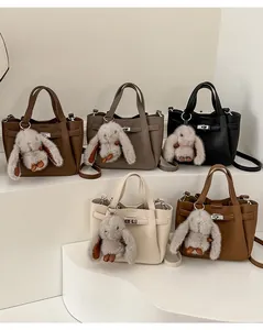 Détail de sacs seaux en cuir grainé en cinq couleurs avec des breloques lapin en peluche