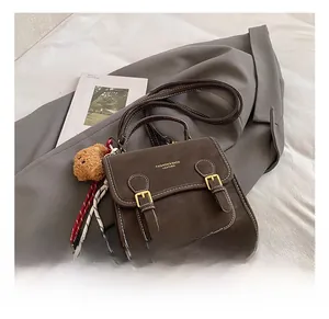 Detail of dark brown vintage leather bag with contrast stitching and bear charm