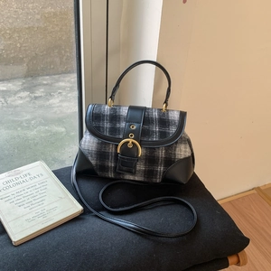 Close-up of retro black and white plaid wool handbag with gold buckle and leather strap