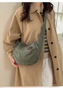 Detail of dark green canvas crescent bag with leather patch and wide shoulder strap