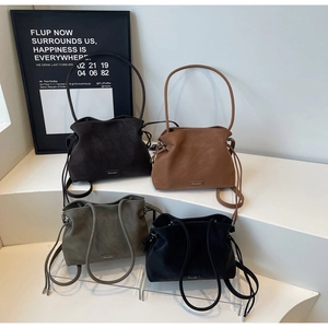 Detail of four matte suede bucket bags in dark brown, tan, olive green, and black colors