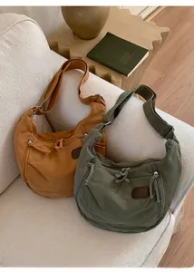 Détail de sacs bandoulière en toile vintage en gingembre et vert olive sur un canapé