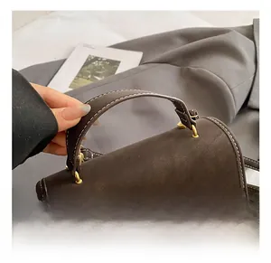 Detail showing dark brown leather texture with white contrast stitching and gold buckle