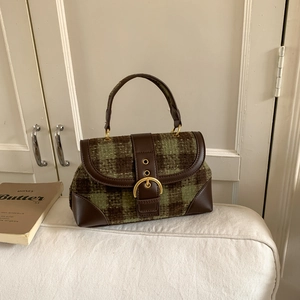 Close-up of green and brown plaid fabric texture with leather strap on a saddle bag