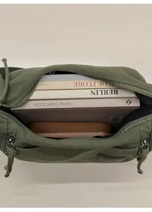 Macro view of spacious dark green canvas bag interior holding books and glasses case