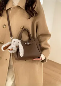 Détail d'un sac seau en cuir marron grainé avec fermoir argenté et charm lapin en peluche