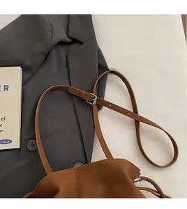 Detail of adjustable long shoulder strap with silver buckle on brown bucket bag