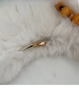Close-up of golden zipper hardware and wooden bead detail on plush dumpling bag